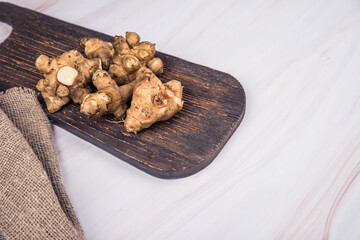 Jerusalem artichoke tubers lie on a wooden board.