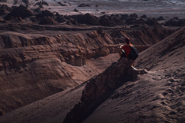 Boy sitting on a rock looking at the canyon in the Atacama desert
