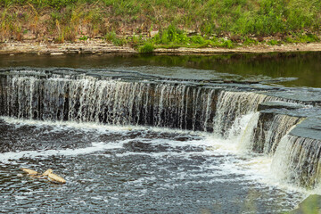 Waterfall on the Tosno River. A river with rapids and a rocky shore. In Sablino, Leningrad region, Russia.