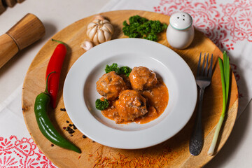 meat balls in sauce on a white plate on a wooden background in a cafe
