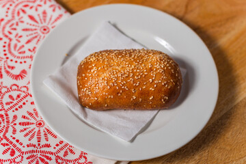 a small pie sprinkled with sesame seeds on a white plate Russian cuisine