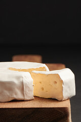 Camembert cheese on wooden cutting board. A sort of cheese French brie. Sliced brie cheese. Close...