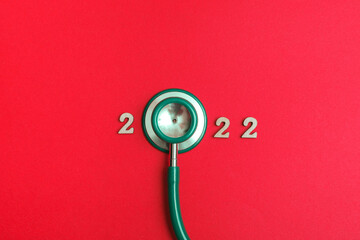 Fototapeta na wymiar Stethoscope number 2022 on red background creative idea new trend medical banner calendar cover closeup with copy space