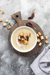 Mushroom cream soup with croutons served on concrete background. Soup in a bowl. Top view 