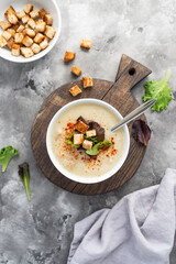 Mushroom cream soup with croutons served on concrete background. Soup in a bowl. Top view 