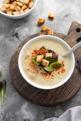 Mushroom cream soup with croutons served on concrete background. Soup in a bowl. Top view 