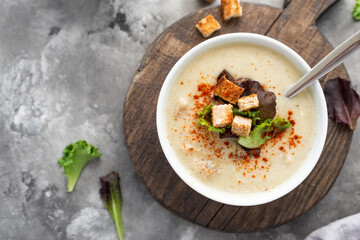 Mushroom cream soup with croutons served on concrete background. Soup in a bowl. Top view 