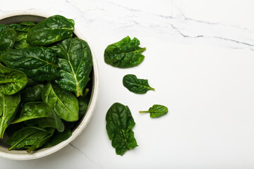spinach leaves in a bowl on a white background top view 