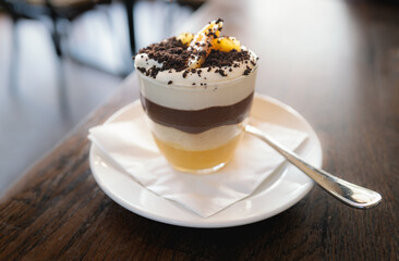Shallow focus on chocolate sprinkles on a clementine and chocolate trifle in a glass on a table in a restaurant.