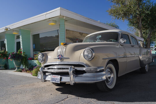 Victorville, California, USA: image of an eraly 50s Pontiac automobile shown parked by the historic diner Holland Burger Cafe.