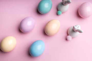 Colored easter eggs with a deco bunny on a pink background. Festive spring decoration , pastel colors .
