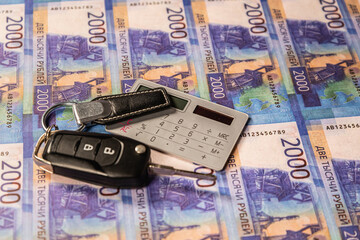 Car keys, money (Russian) and calculator. Selling, buying and renting a car.