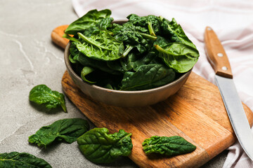 Organic food concept with spinach leaves in a bowl on a cutting board with a knife on a gray...