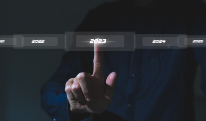 Finger pressing blue start 2023 button on virtual interface on gray background with copy space for text. Concept of new year. Businessman pressing 2023 start up business. Beginning of New Year 2023