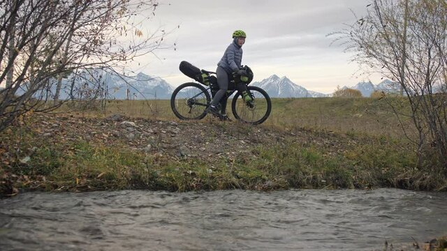 The woman travel on mixed terrain cycle touring with bikepacking. The traveler journey with bicycle bags. Sport tourism bikepacking.