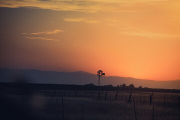 Mountain Sunset with Silhouetted Windmill and Clouds in a Colorful Sky