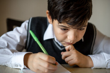 a student in a school uniform at home does homework at the table