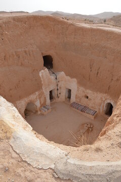 Underground Troglodyte house inner yard in Tunisia, Africa, rooftop Yellow sand, brown earthen and white plastered walls
