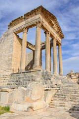 Fototapeta premium Temple of Jupiter and ancient roman ruins of Dougga in Tunisia, Africa in the sunny afternoon. Blue sky with clouds, old yellow, grey and brown stone walls and columns 
