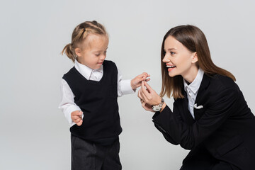joyful mother holding hands with disabled daughter isolated on grey.