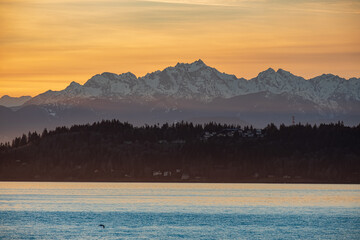 Sun sets over Puget Sound and the Olympic Mountains with colorful skies and a fishing pier - obrazy, fototapety, plakaty