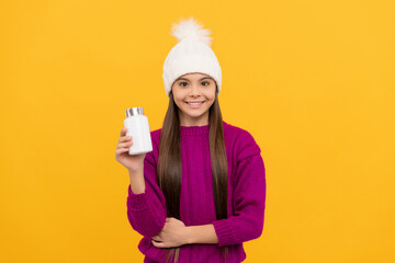 smiling child in winter hat with pill jar. food supplement. teen girl with natural pill products.