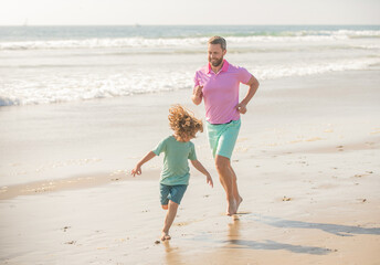 father and son running on morning beach. family travel weekend and vacation.