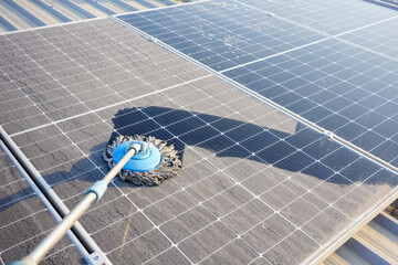 Man clean up the solar panels that are dirty with dust and birds' droppings to improve the...