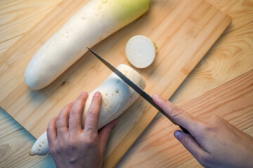 Fresh white daikon radish with slice on the wooden background. Hand cut Korean radishes with a...