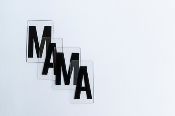 Conjunto de letras aisladas formando la palabra MAMA. cuatro láminas de plástico transparente con tipografía