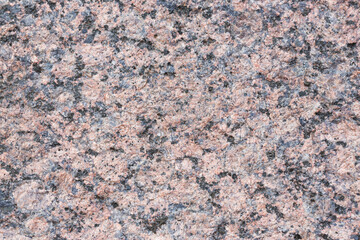 Granite texture. Natural pink granite with a grainy pattern. Stone background. Solid rough surface of rock. Durable construction and decoration material. Close-up.