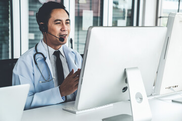 Doctor wearing headset talking actively on video call in a clinic or hospital . Concept of...