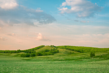 A beautiful green field with hills and a sky with clouds.