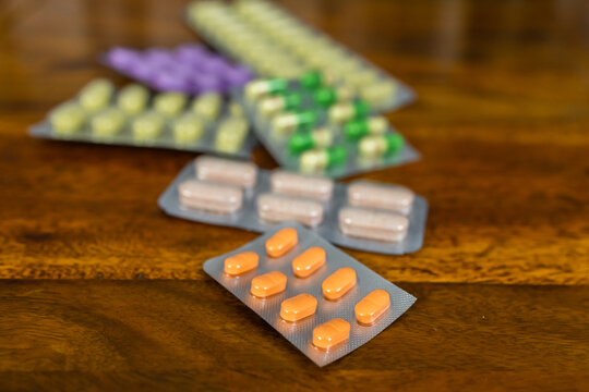 Various types and colors of Allopathic medicines displayed on a wooden background