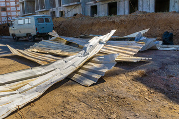 deformed metal profiled sheets lie at a dead end after the dismantling of the temporary fence of the construction site, selective focus