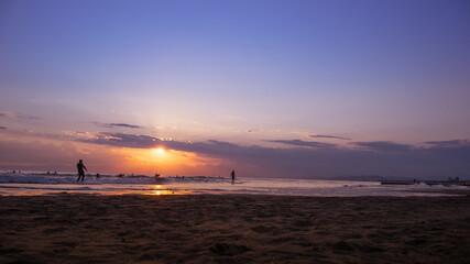 Naklejka premium 日本の綺麗な夕日と海岸の景色 サーフィンを楽しみむ人のシルエット