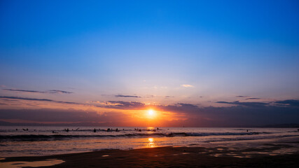 日本の綺麗な夕日と海岸の景色　サーフィンを楽しみむ人のシルエット