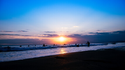 日本の綺麗な夕日と海岸の景色　サーフィンを楽しみむ人のシルエット