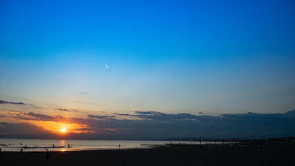 日本の綺麗な夕日と海岸の景色　サーフィンを楽しみむ人のシルエット