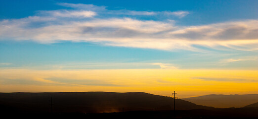 sunset over the mountains with a cloudy sky
