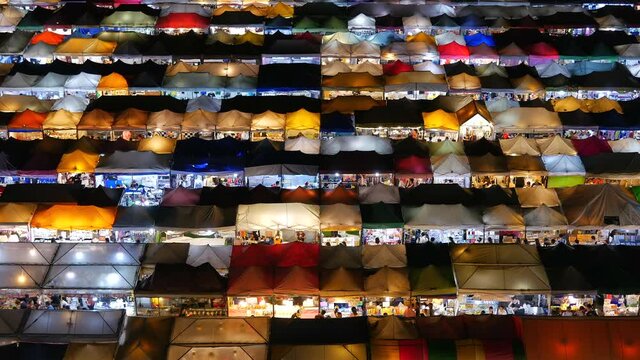 Aerial view of colourful stalls at the famous Ratchada Train Night Market in Bangkok, Thailand, establishing shot. 