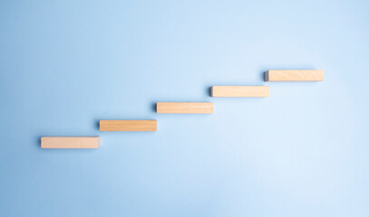 Wooden pegs place over navy blue background in a stairway like structure in a conceptual image. With copy space.