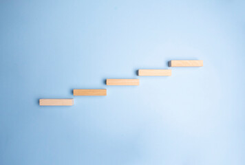 Wooden pegs place over navy blue background in a stairway like structure in a conceptual image. With copy space.
