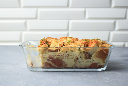 Selected Focus Homemade Savory Bread Pudding With Sausage And Shredded Cheddar Cheese, Served On Clear Baking Dish