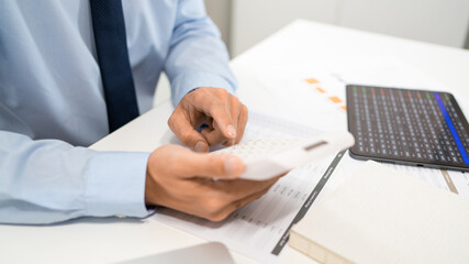 Working Man Conept The male officer sitting at his desk, holding the calculator, and pressing it