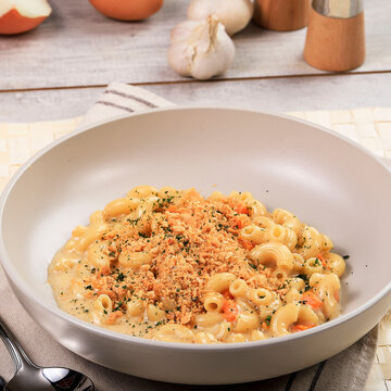 Mac and Cheese with Bread Crumbs, Oregano Garnish, on White Wood Surface
