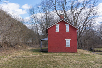 Obraz premium The lockhouse at Lock 31 on the Chesepeake and Ohio canal. Painted red with white wood slated doors and a black roof.