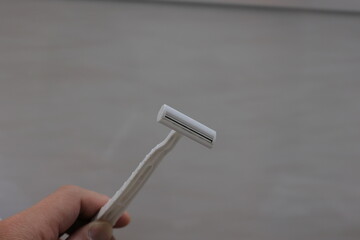 T字カミソリを持つ男性の手