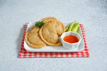 a plate of fried pastries containing vegetables served with sauce against white background