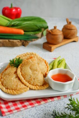 a plate of fried pastries containing vegetables served with sauce against white background